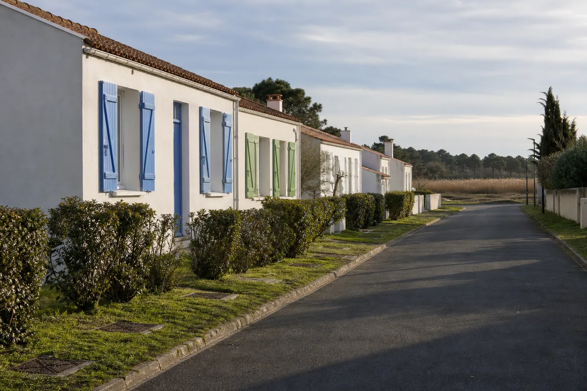 Rue de lotissement à Challans bordée de maisons de plain-pied blanchies à la chaux aux volets bleus