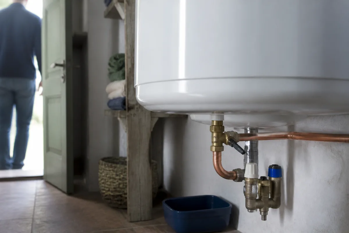 Local technique d’une maison de location : ballon d’eau chaude, tuyauterie cuivre et vanne en laiton