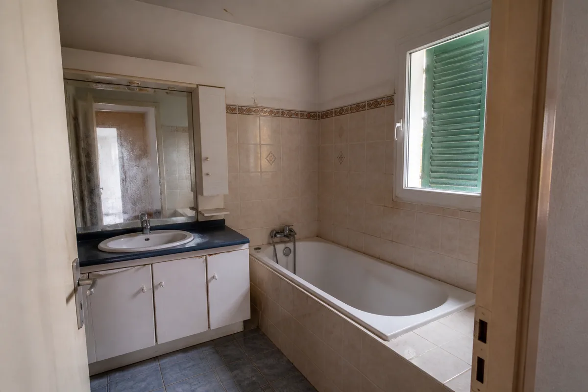 Salle de bain ancienne d&rsquo;un pavillon vendéen avec baignoire encastrée et faïence d&rsquo;époque